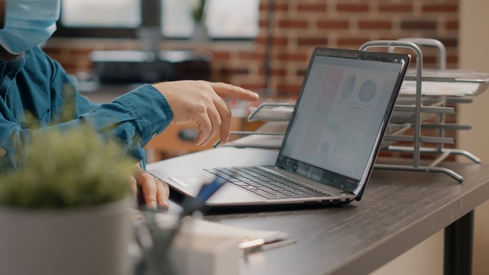 Closeupofemployeeworkingwithlaptopandchartsfiles Payoutscom Closeupofemployeeworkingwithlaptopandchartsfiles